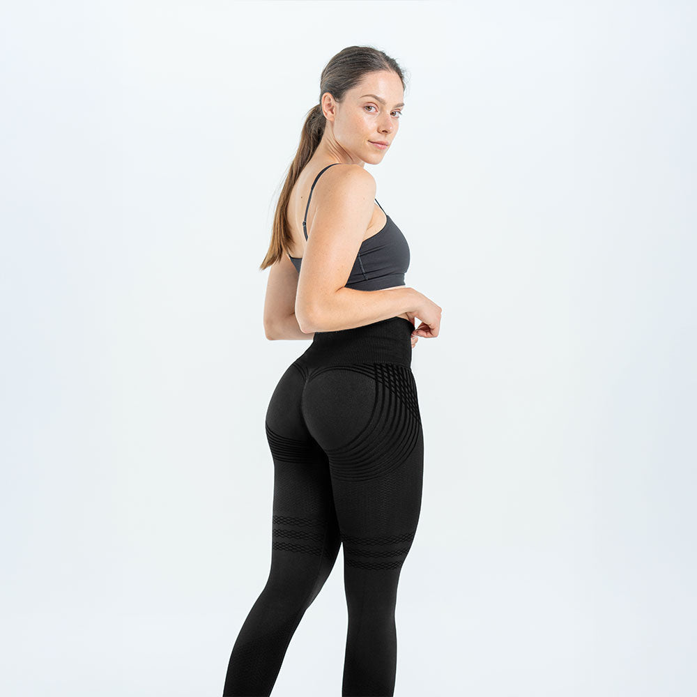 Side view of the black 3D legging, a hand adjusting the high waistband